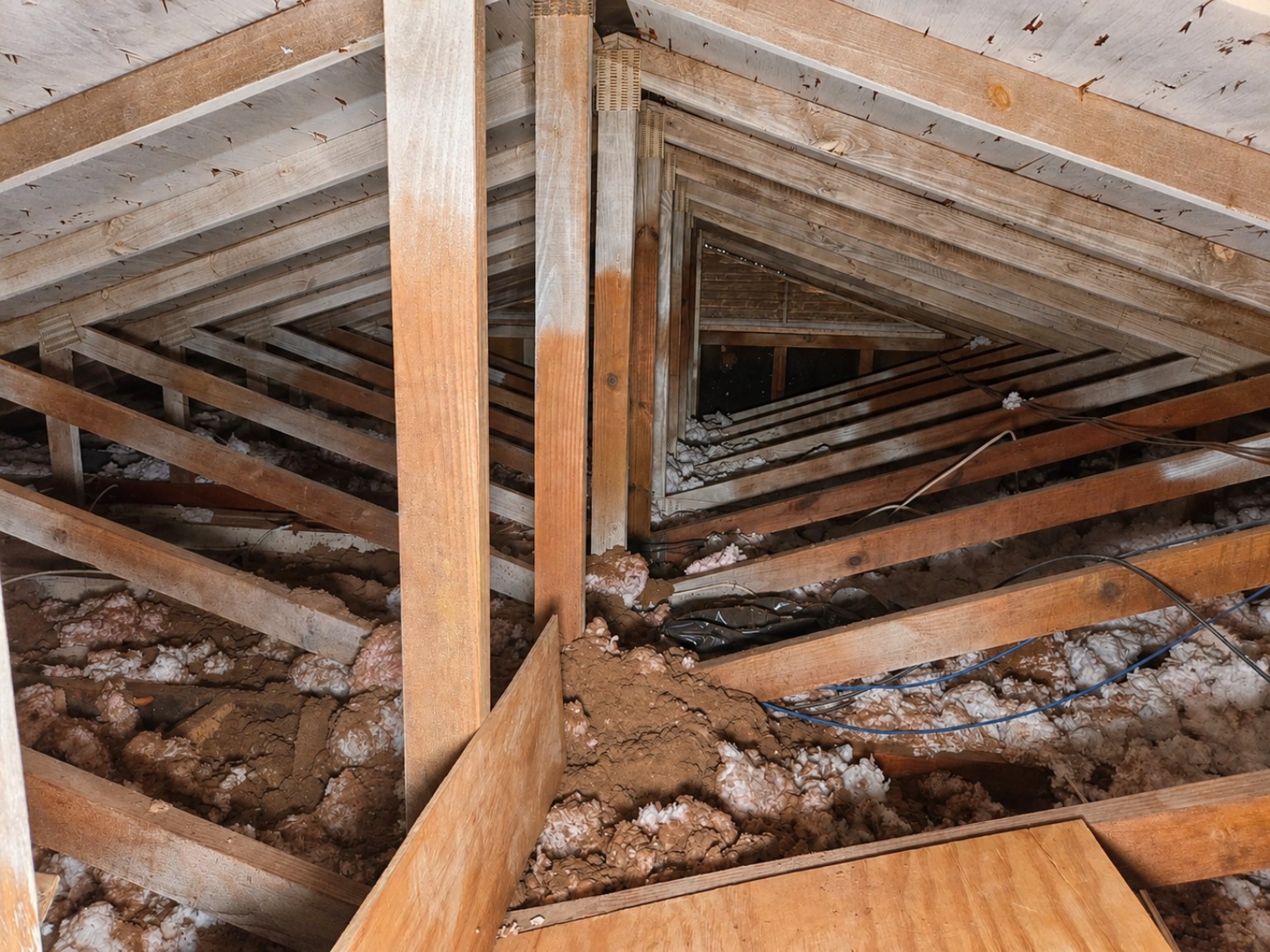 Charlotte attic before Carolux insulation, showing thin, settled coverage between the joists